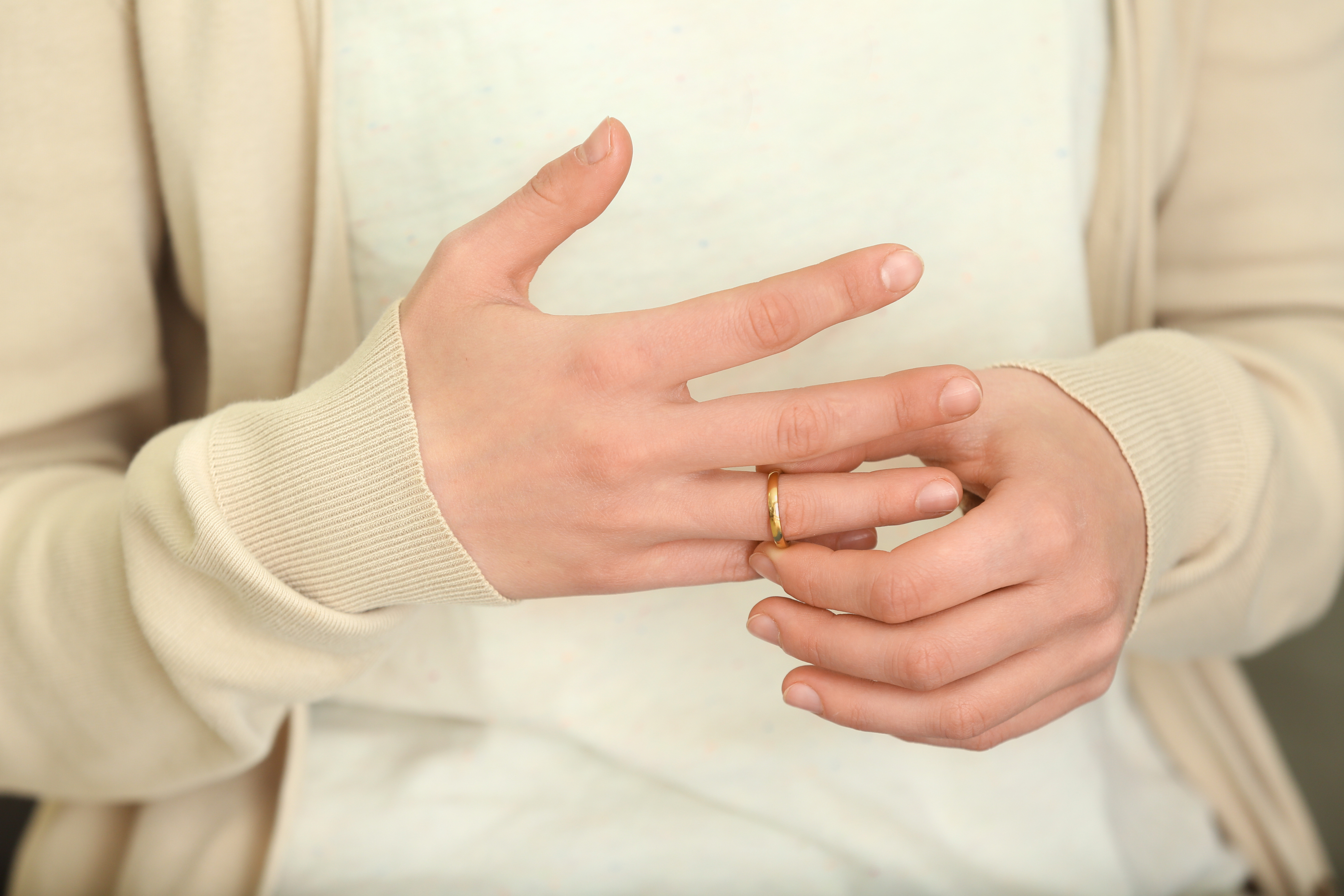 Woman trying to slip ring off her finger, closeup. Concept of divorce