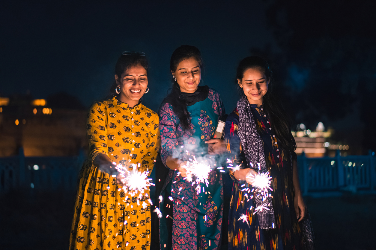 Three young Indian women with bengal fireworks, celebrating Indian Festival Diwali. Three girls are looking at fireworks.
